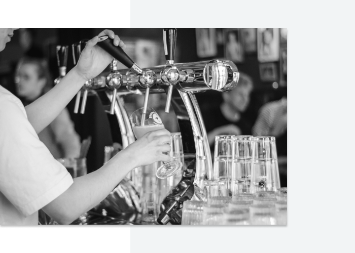 Close-up photo of young guy pouring beer behind a bar, the result of a well-written bartender job description