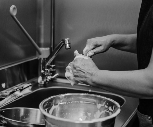Close up of kitchen assistant's hands washing pots